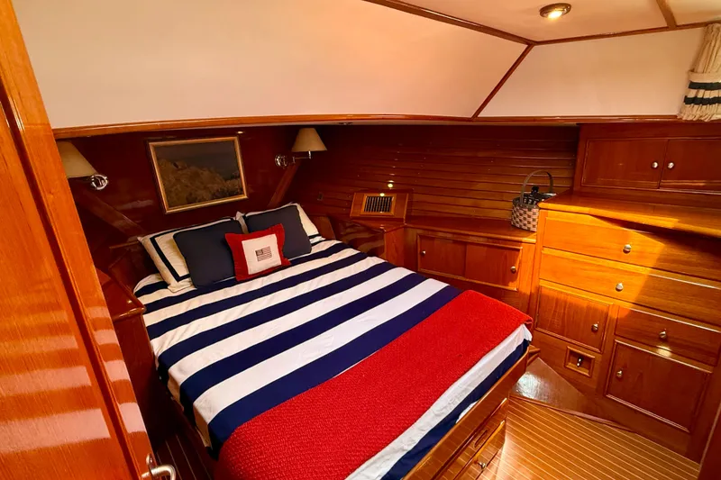 Slide: The Image of Luxurious 2001 Grand Banks 49 Eastbay HX cabin with striped bedding and elegant wood finish. - 35