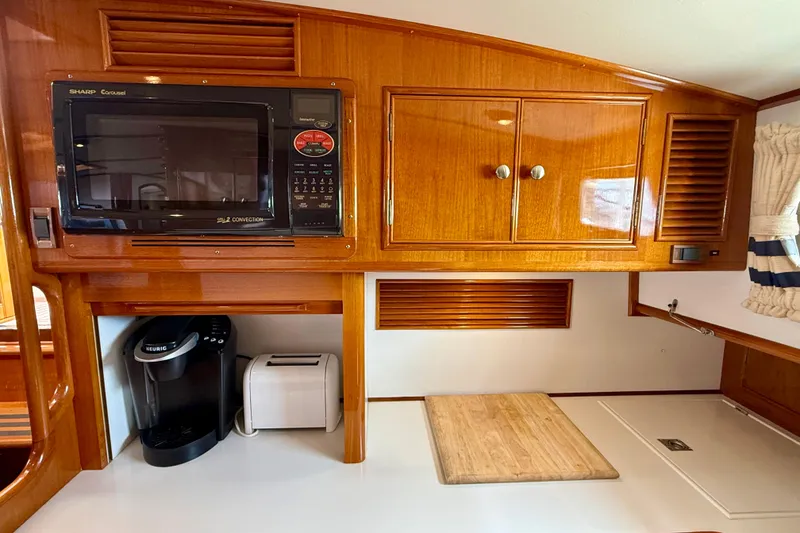 Slide: The Image of Wood-paneled kitchen area in 2001 Grand Banks 49 Eastbay HX with microwave and appliances. - 57