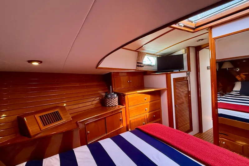 Slide: The Image of Luxurious 2001 Grand Banks 49 Eastbay HX yacht cabin with wood paneling and striped bedding. - 37