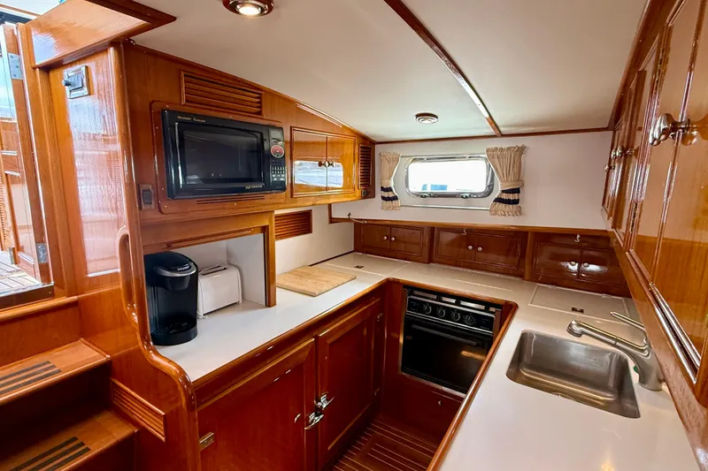 Slide: The Image of Luxurious 2001 Grand Banks 49 Eastbay HX yacht kitchen with wood cabinetry and modern appliances. - 53
