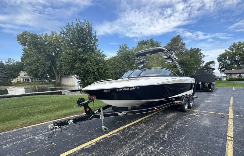 Slide: The Image of A 2007 Malibu Wakesetter 23 LSV on a trailer in a parking lot, surrounded by trees. - 1