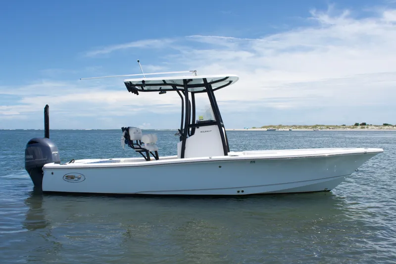 Slide: The Image of 2024 Sea Hunt BX22BR boat on calm water under a clear blue sky. - 2