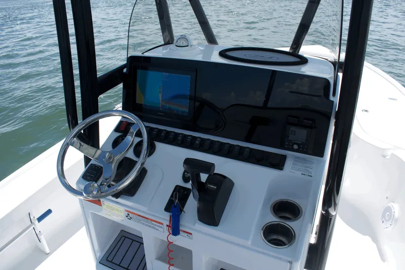 Slide: The Image of 2024 Sea Hunt BX22BR boat console with steering wheel and navigation display on water. - 12
