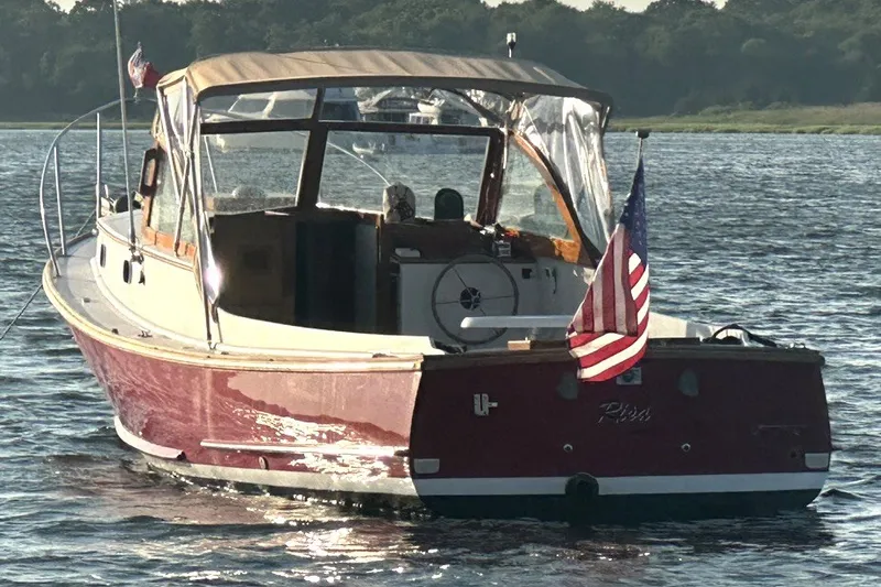 Slide: The Image of Classic 1974 Wasque 32 boat with American flag on calm water. - 1