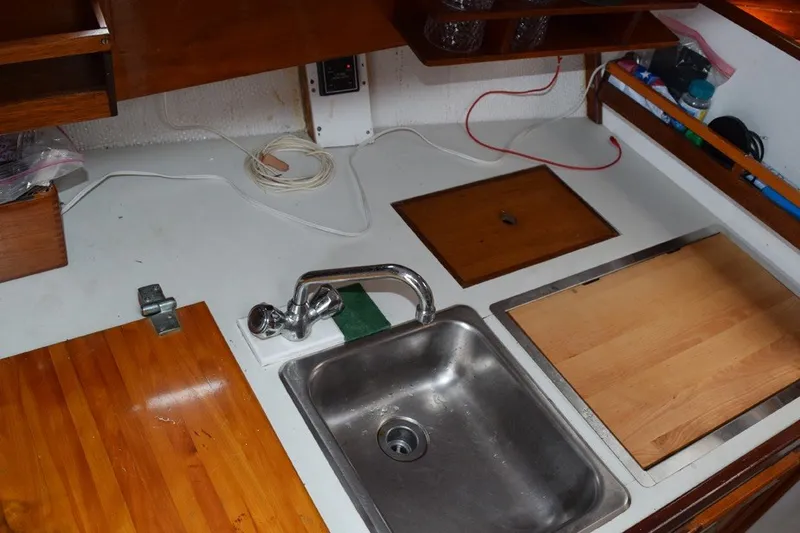 Slide: The Image of 1974 Wasque 32 boat galley with sink, wooden countertops, and storage compartments. - 23
