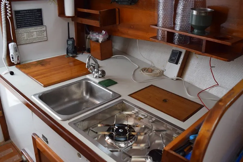 Slide: The Image of 1974 Wasque 32 boat kitchen with sink, stove, and wooden shelves. - 25