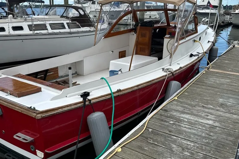 Slide: The Image of 1974 Wasque 32 boat docked, featuring a red hull and wooden accents. - 2