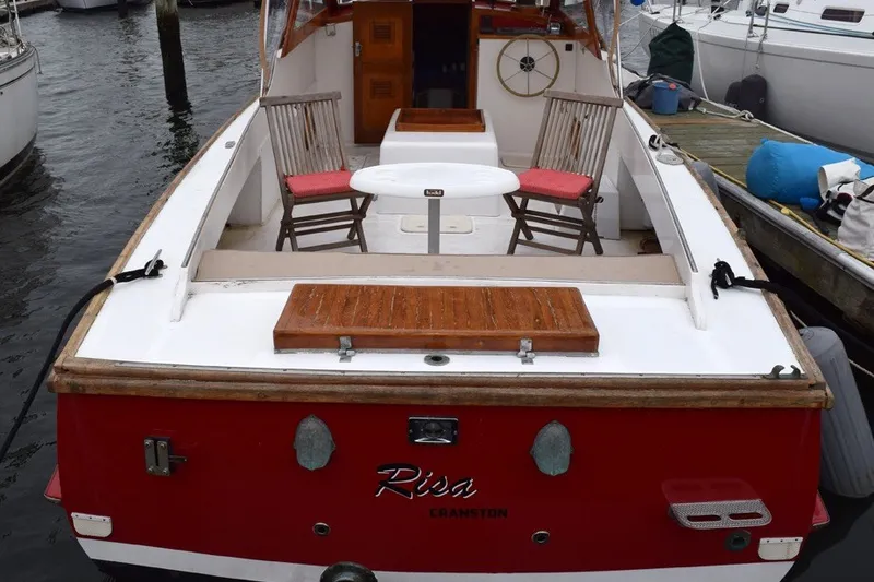 Slide: The Image of 1974 Wasque 32 boat with red hull, docked, featuring wooden deck and seating area. - 4