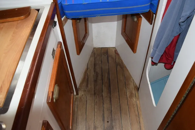 Slide: The Image of 1974 Wasque 32 boat interior with wooden flooring and blue cushioned seating. - 29
