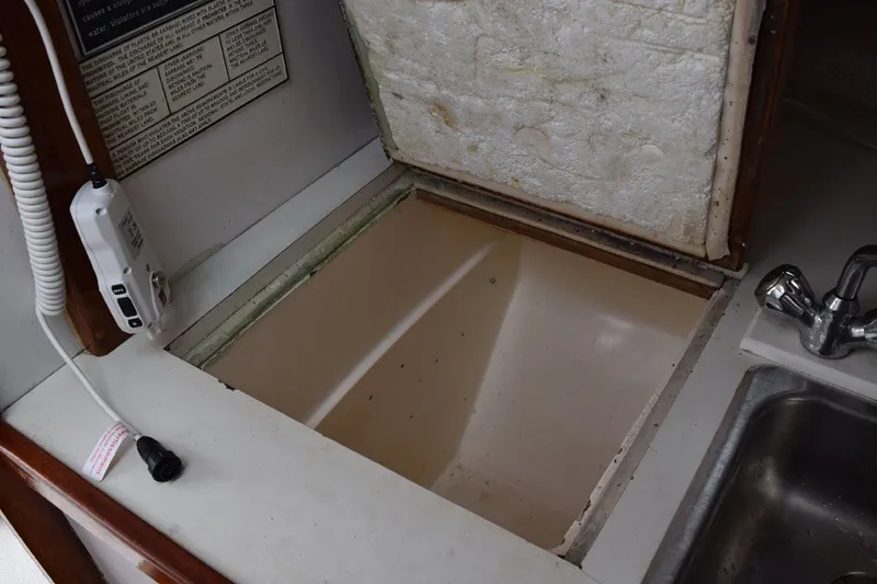 Slide: The Image of 1974 Wasque 32 boat interior with open storage compartment and sink. - 27