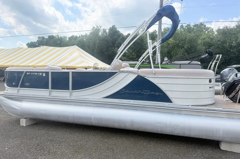 Slide: The Image of 2017 South Bay 500 pontoon boat with blue and white design, parked outdoors. - 3