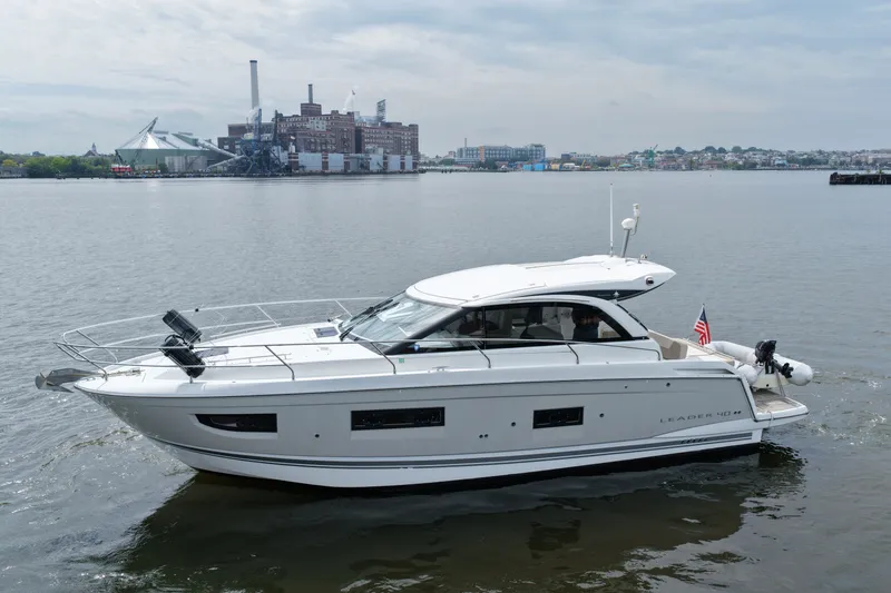 The Image of 2015 Jeanneau Leader 40 yacht cruising on a calm river with industrial backdrop. - 0