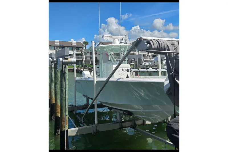 Slide: The Image of 2019 Contender 30 ST boat on lift, docked near waterfront buildings under blue sky. - 17