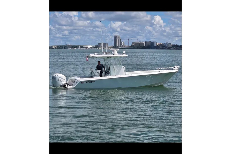 Slide: The Image of 2019 Contender 30 ST boat cruising on a calm sea with city skyline backdrop. - 14