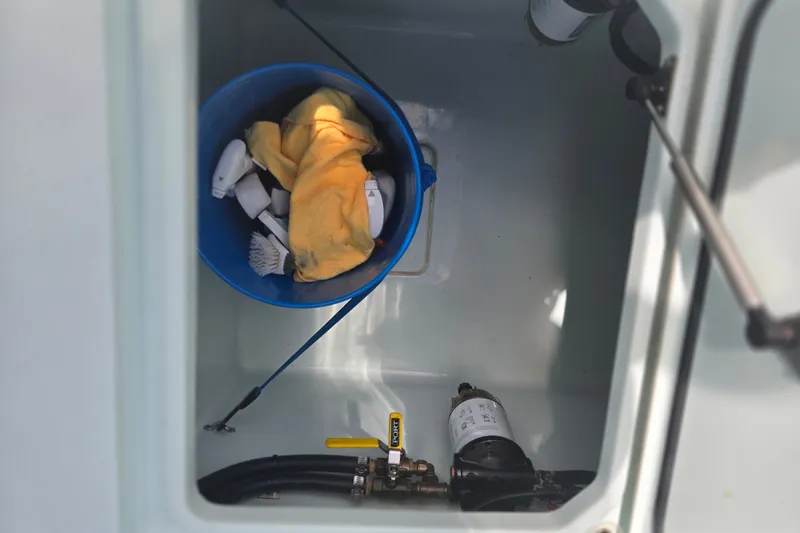 Slide: The Image of Storage compartment of 2019 Contender 30 ST boat with cleaning supplies in a blue bucket. - 76