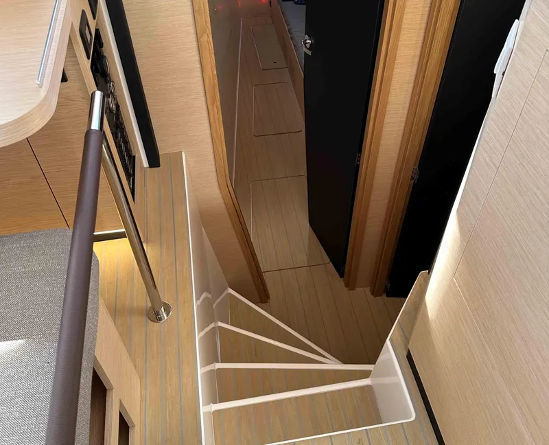 Slide: The Image of Interior of NEEL 52 yacht, 2025 model, featuring modern staircase and wooden finishes. - 14