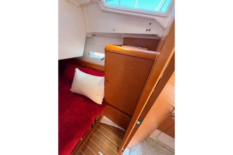 Slide: The Image of Cozy cabin interior of 2014 Jeanneau Sun Odyssey 509 with red bedding and wooden cabinetry. - 69