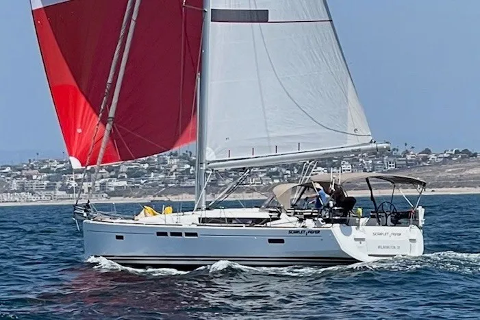 Slide: The Image of 2014 Jeanneau Sun Odyssey 509 sailing with red and white sails on open water. - 2