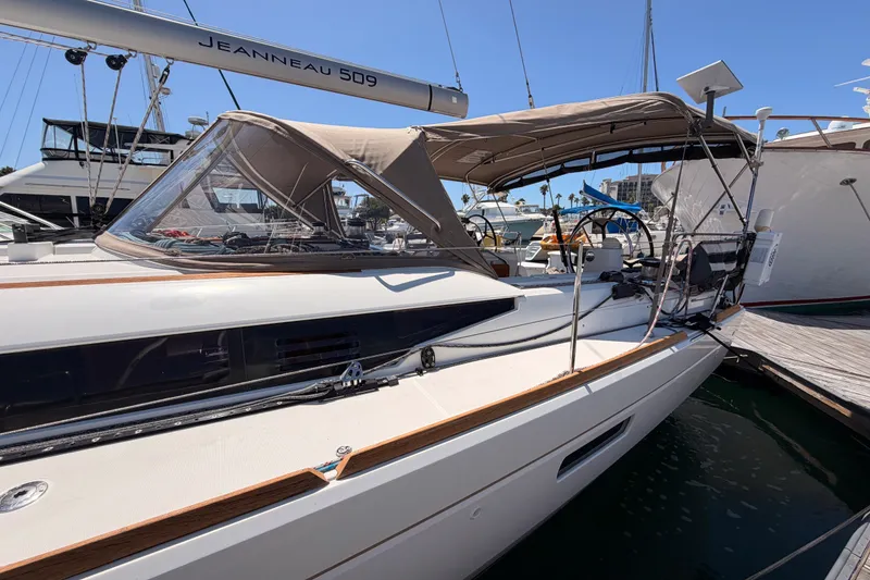 Slide: The Image of 2014 Jeanneau Sun Odyssey 509 sailboat docked at marina, featuring sleek design and canopy. - 13