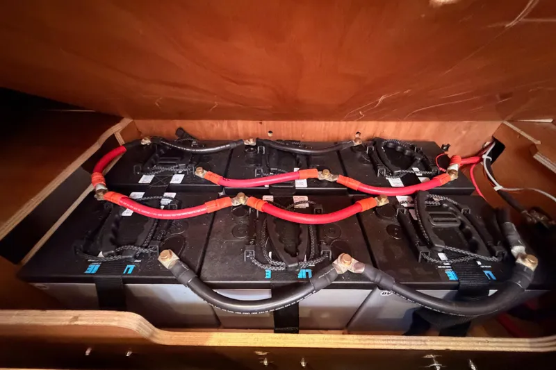 Slide: The Image of Battery compartment of a 2014 Jeanneau Sun Odyssey 509 sailboat, featuring multiple connected batteries. - 103