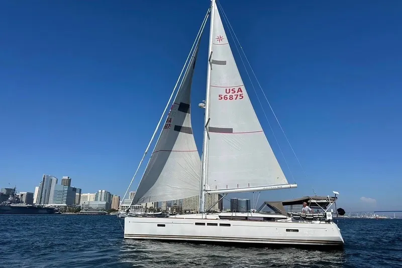The Image of 2014 Jeanneau Sun Odyssey 509 sailing near city skyline under clear blue sky. - 1