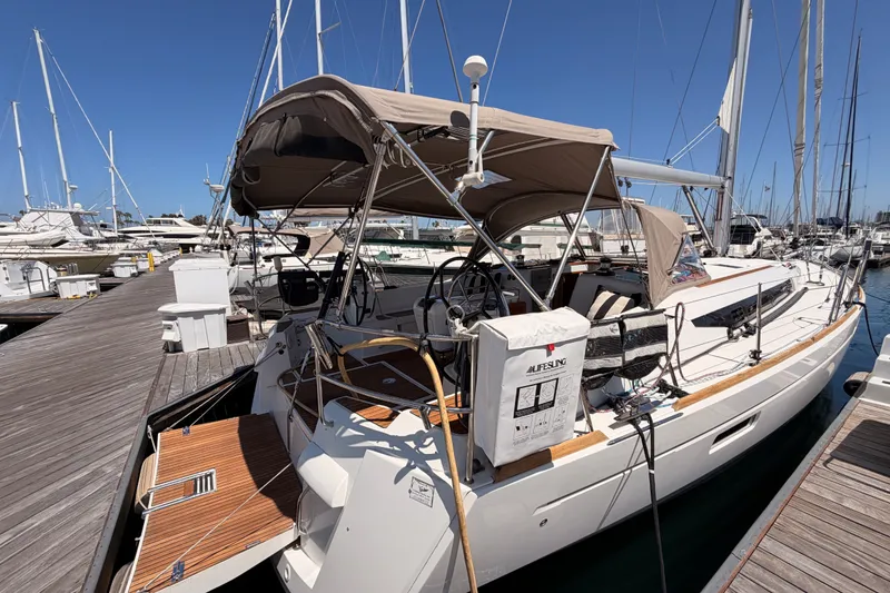 Slide: The Image of 2014 Jeanneau Sun Odyssey 509 sailboat docked at marina, featuring spacious deck and canopy. - 16