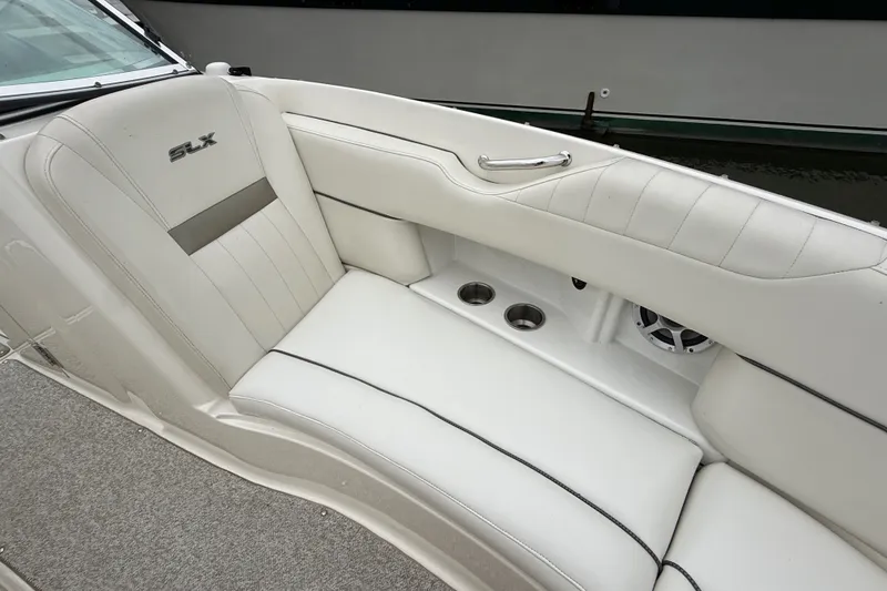 Slide: The Image of Luxurious white seating on a 2007 Sea Ray SLX 250 boat, featuring cup holders and speaker. - 28