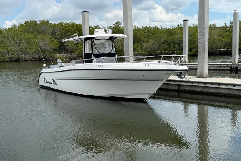 The Image of 2006 Century 3200 Center Console boat docked in calm waters, surrounded by greenery. - 1