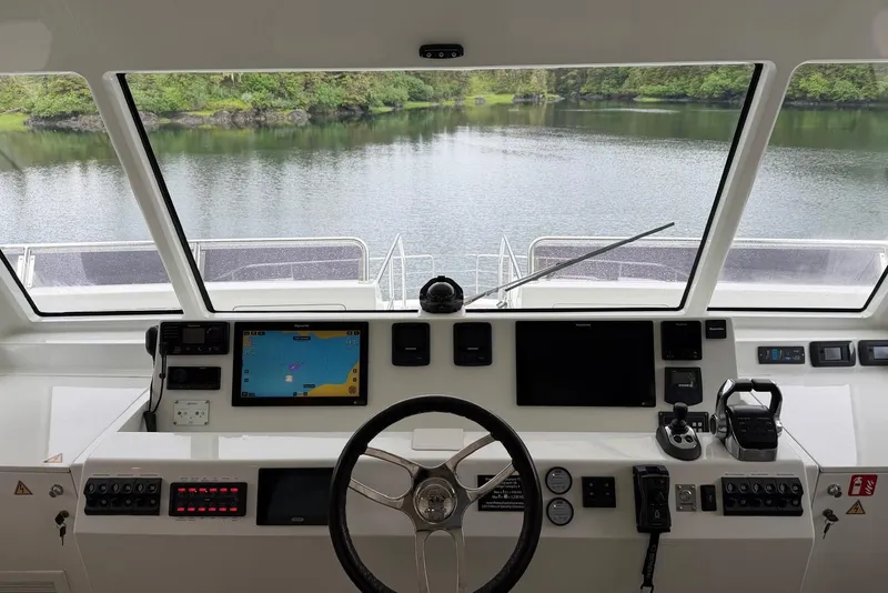 Slide: The Image of Cockpit view of 2023 Longreach 58 Expedition yacht, featuring navigation controls and serene water scenery. - 24