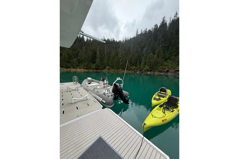 Slide: The Image of Deck view from 2023 Longreach 58 yacht with kayaks and inflatable boats on serene water. - 78