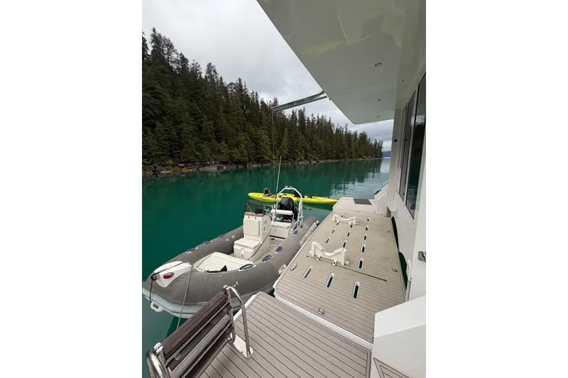 Slide: The Image of Luxury Longreach 58 yacht deck with inflatable boat, serene forested lake view, 2023 model. - 77