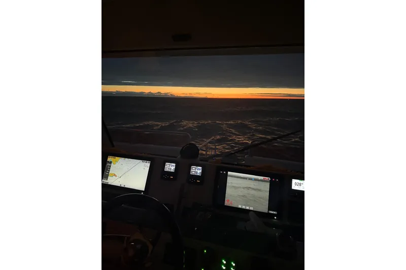 Slide: The Image of Cockpit view from 2023 Longreach 58 boat at sunset, featuring navigation screens. - 13
