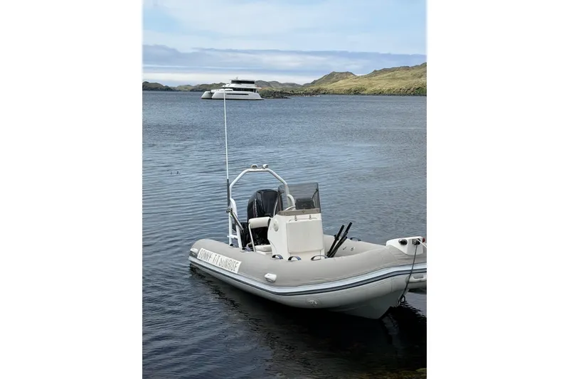 Slide: The Image of A 2023 Longreach 58 boat anchored on a serene lake with distant hills. - 79