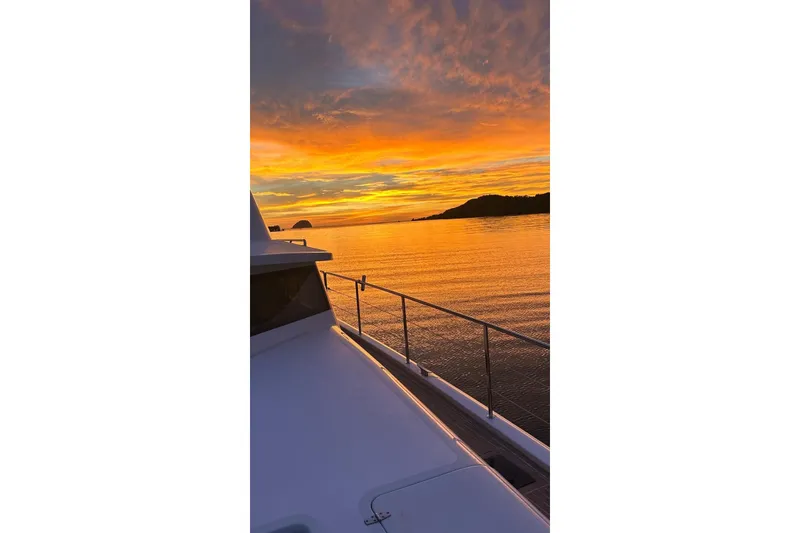 Slide: The Image of Longreach 58 yacht at sunset, 2023, with vibrant orange sky and calm waters. - 11