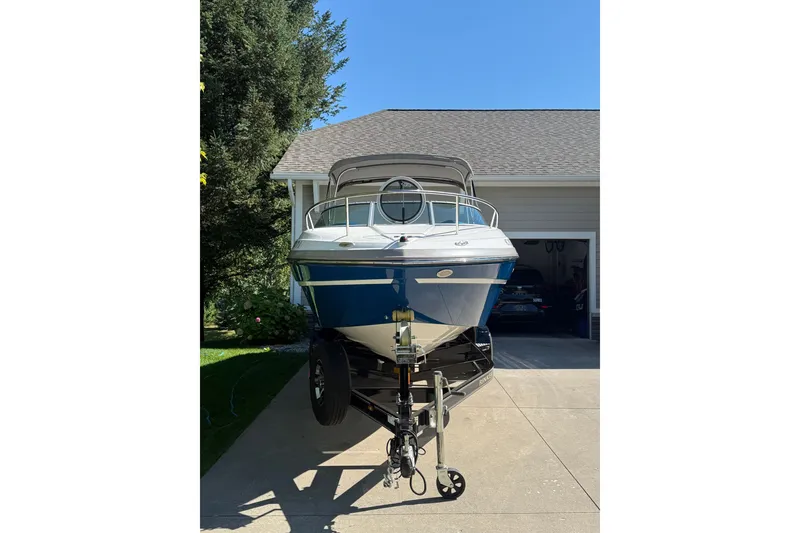 Slide: The Image of 2017 Rinker QX23 CC boat on trailer in driveway, sunny day. - 23