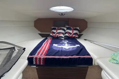 Slide: The Image of 2017 Rinker QX23 CC cabin interior with nautical-themed bedding and pillows. - 19