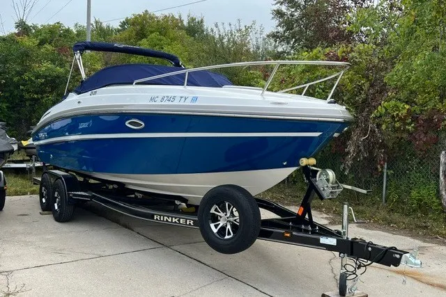 Slide: The Image of 2017 Rinker QX23 CC boat on trailer, blue and white, parked outdoors. - 3