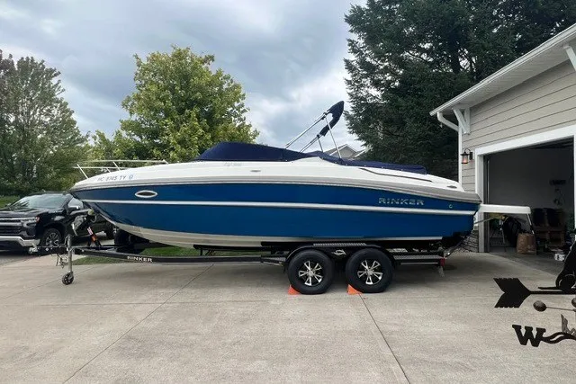 Slide: The Image of 2017 Rinker QX23 CC boat on trailer in driveway, blue and white design. - 4