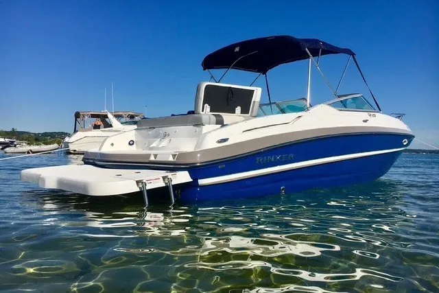 The Image of 2017 Rinker QX23 CC boat with blue hull, anchored in clear water under a sunny sky. - 1