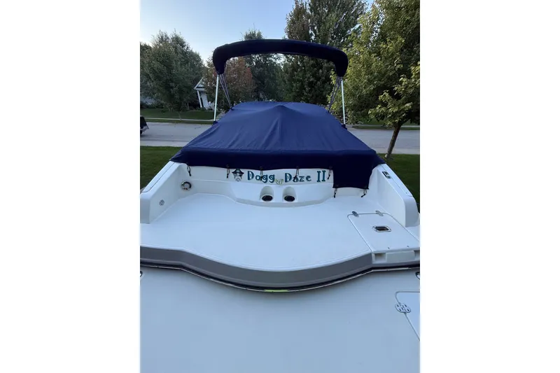 Slide: The Image of 2017 Rinker QX23 CC boat with blue cover, parked outdoors. - 25