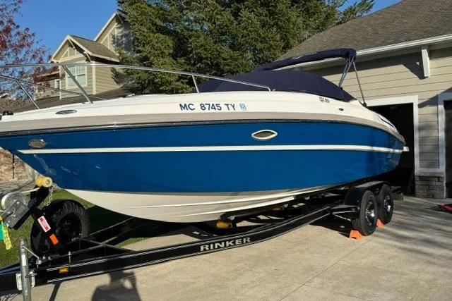 Slide: The Image of 2017 Rinker QX23 CC boat on trailer, blue and white, parked in driveway. - 5