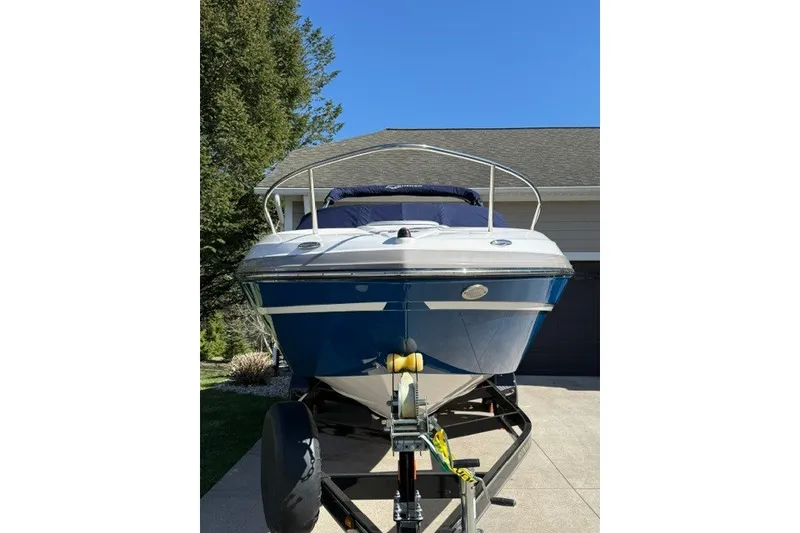 Slide: The Image of 2017 Rinker QX23 CC boat on trailer, parked in driveway under clear blue sky. - 9