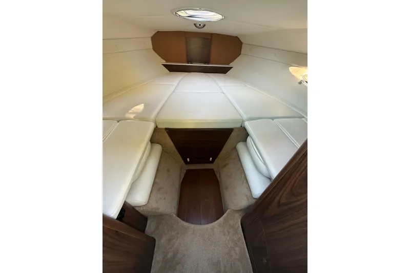 Slide: The Image of 2017 Rinker QX23 CC cabin interior with white seating and wood accents. - 18