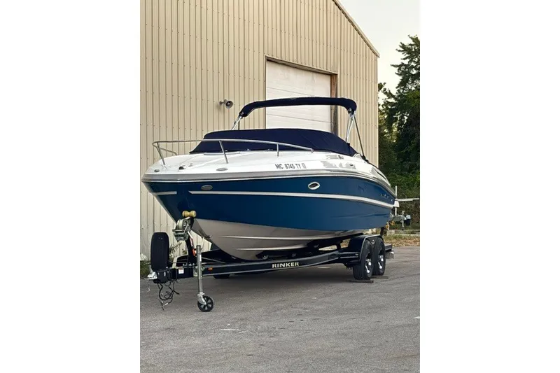 Slide: The Image of 2017 Rinker QX23 CC boat on trailer, parked outside a large building. - 6