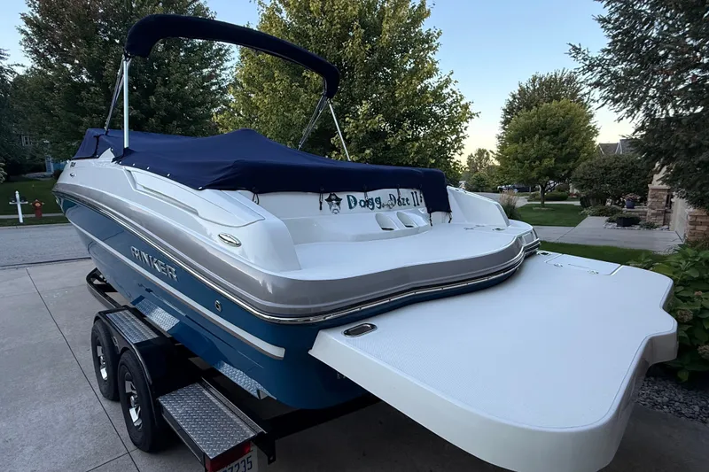 Slide: The Image of 2017 Rinker QX23 CC boat on trailer with blue cover, parked in driveway. - 13