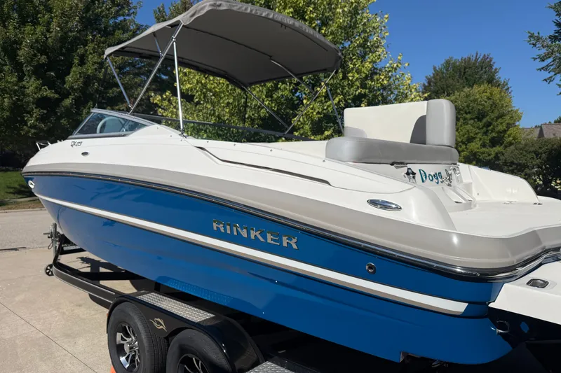 Slide: The Image of 2017 Rinker QX23 CC boat with blue hull and canopy, parked on a trailer. - 7