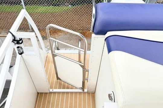 Slide: The Image of 2006 JC 23 Neptoon TT boat interior with blue and white seating, open gate, and wooden flooring. - 18