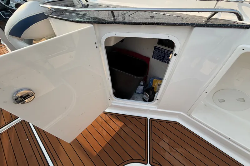 Slide: The Image of Open storage compartment on 2013 Monterey 264FSX boat with visible cleaning supplies. - 10
