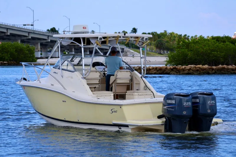 Slide: The Image of 2003 Scout 280 Abaco boat with dual Yamaha engines cruising near a bridge. - 3