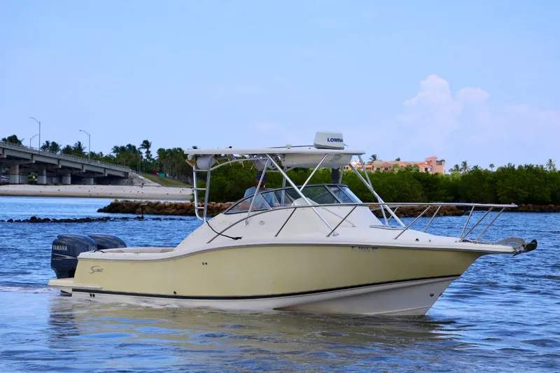 Slide: The Image of 2003 Scout 280 Abaco boat cruising on a scenic waterway with a bridge in the background. - 2